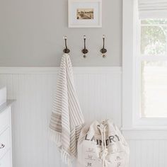 a white and gray bathroom with two towels hanging on the wall next to a window