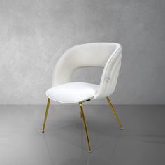 a white chair with gold legs in front of a gray wall and concrete flooring