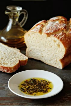 two loaves of bread on a table next to a bowl of oil and pepper