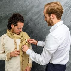 two men standing next to each other in front of a wall