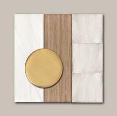 a white marble and wood wall panel with a gold plate on the top, next to it