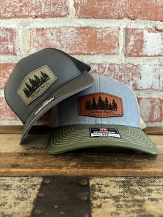 Evergreen tree line genuine leather patch hat. Many genuine leather patch and Richardson 112 hat color styles to choose from. Choose which patch color to put with each hat. American owned and operated with fast turnaround. Leather Hat Patch Designs, Trucker Style Baseball Cap With Patches For Outdoor, Trucker Baseball Cap With Patches For Outdoor, Outdoor Trucker Snapback Hat With Patches, Outdoor Trucker Hat With Patches And Curved Brim, Country Style Trucker Hat With Curved Bill For Outdoor, Outdoor Six-panel Hat With Leather Patch, Outdoor Flat Bill Hats With Patches, Outdoor Trucker Hat With Leather Patch And Flat Bill