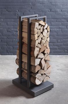 a stack of firewood sitting on top of a metal stand next to a brick wall