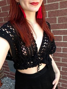 a woman with red hair is posing for the camera, wearing black clothing and earrings