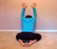 a person sitting on the floor with their arms in the air and hands above their head