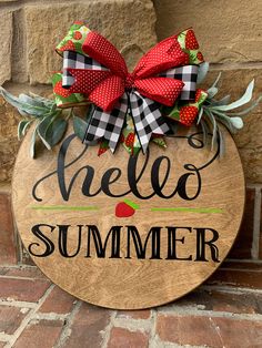 a wooden sign that says hello summer on the side of a brick wall with a red bow