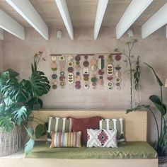 a living room filled with lots of plants next to a wall mounted art piece on the wall