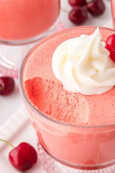 a close up of a dessert in a glass with whipped cream and cherries on top