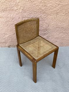 a wooden chair sitting on top of a blue and white floor next to a pink wall