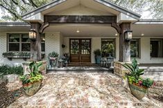 a white house with two large planters on the front porch and an entry way