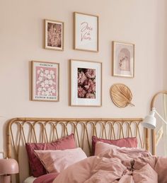 a bed with pink linens and pictures on the wall above it in a bedroom