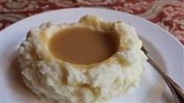 a plate with mashed potatoes and gravy on it next to a fork