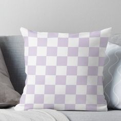 a pink and white checkered pillow sitting on top of a couch