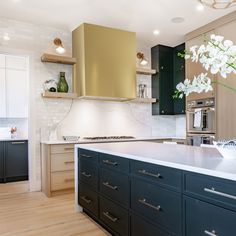 a kitchen with wooden floors and white counter tops, black cabinets and gold backsplash