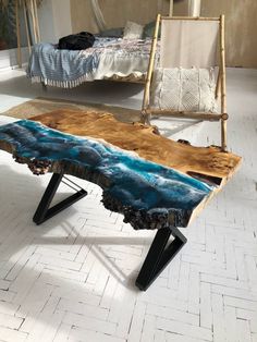 a table made out of wood with blue paint on it and two chairs in the background