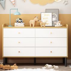 a white dresser sitting in a bedroom next to a wall with pictures and toys on it