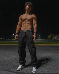 a shirtless man standing in the middle of a parking lot with his hands on his hips