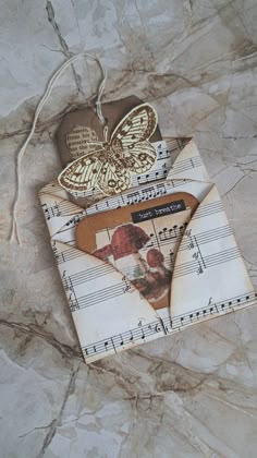 an envelope with sheet music notes and a butterfly on the front is sitting on a marble surface