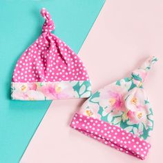 two baby hats with pink flowers and polka dots on them, one has a bow at the top