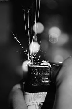 a person holding a lighter in their hand with some sparklers coming out of it