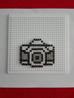 a white plate topped with a black and white cross stitched design on top of a red table cloth