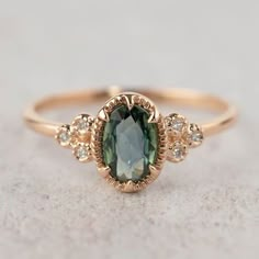 a ring with an oval green stone surrounded by small white and brown diamonds on top