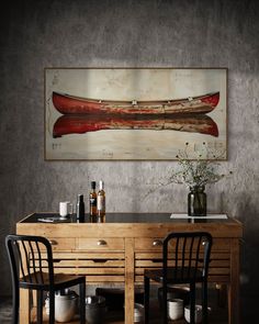 a dining room table with two chairs and a painting on the wall above it that says canoe