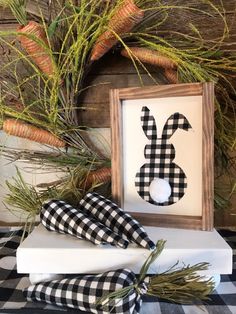 a black and white checkered table cloth with a wooden frame holding an easter bunny sign