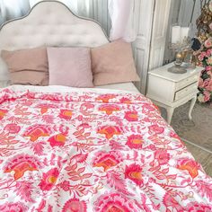 a bed with pink and orange bedspread in a bedroom next to a white dresser