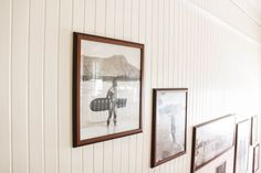 three framed photographs hang on the wall next to each other, with one person holding a surfboard