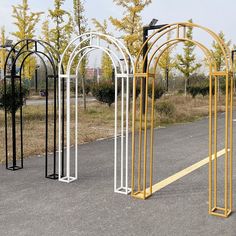 four metal archways sitting on the side of a road