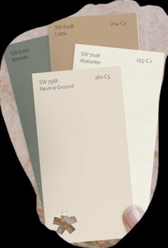 a hand holding some paint samples on top of a white plate with brown and beige colors