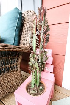 a pink planter sitting on top of a wooden bench next to a wicker chair