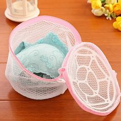 two mesh storage bags sitting on top of a wooden table next to flowers and candles