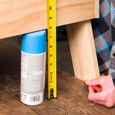 a person measuring the height of a wooden table with a tape measure ruler on it