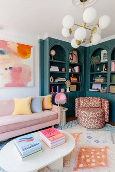 a living room filled with furniture and bookshelves next to a painting on the wall