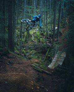 a man riding a bike over a wooden bridge in the woods