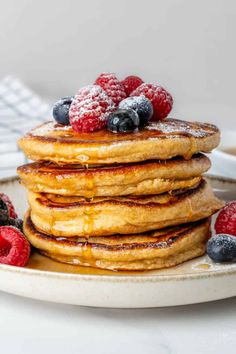 stack of pancakes topped with berries and powdered sugar