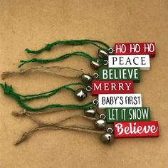 small christmas bells with green string and sayings on them sitting on a brown surface