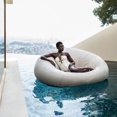 a man sitting on an inflatable chair next to a swimming pool