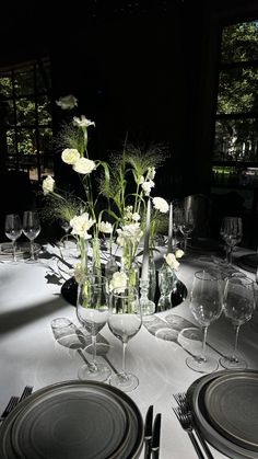 the table is set with white flowers and wine glasses, silverware, and place settings