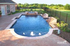 a backyard with a swimming pool surrounded by landscaping