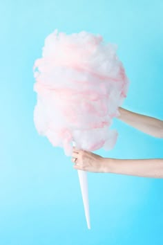 a person holding a cotton candy pinata on a stick with the words diy cotton candy pinata