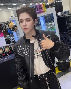 a man in black leather jacket giving the thumbs up sign at an electronics showroom