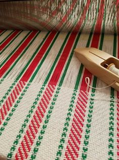 a pair of scissors sitting on top of a red and green striped table cloth next to a sewing needle