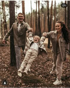 a man, woman and child are playing in the woods