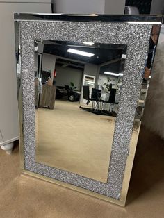 a large mirror sitting on top of a carpeted floor next to a white chair