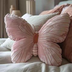 a pink butterfly pillow sitting on top of a bed