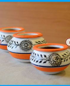 three orange and white vases sitting on top of a table