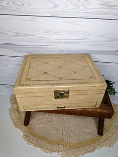 a wooden box sitting on top of a doily next to a white wood wall